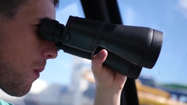 A young man looks through binoculars, watches and chews food. HD, 1920x1080. Slow motion — Stock Video