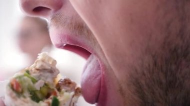 Genç bir adam, öğle yemeğinde bir lezzetli sulu shawarma ısırıkları yakın çekim. ağır çekim. 1920 x 1080. hd tam