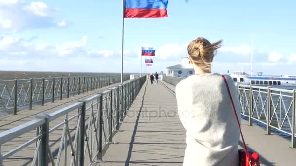 Das Mädchen läuft an der Mole entlang, der starke Wind bläst, die russische Flagge entwickelt sich. Zeitlupe. 1920x1080. Voll hd — Stockvideo