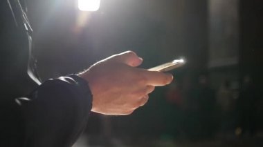 Telefonda tutun bir karşı karanlık bir arka plan, bir ışık huzmesi uçan toz el mans. ağır çekim, 1920 x 1080, tam hd