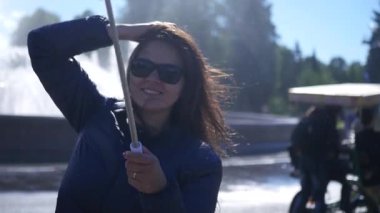 Genç kız kendinden tahrikli ile deniz kenarında parkta telefonda poz. 1920 x 1080. hd tam