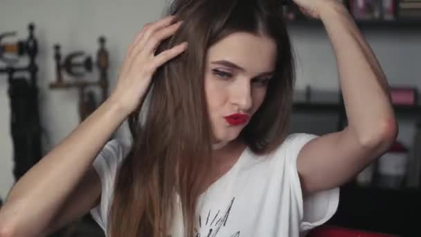 Молода красива дівчина сидить перед дзеркалом, торкаючись її волосся танцює в хорошому настрої. 3840x2160, 4К — стокове відео