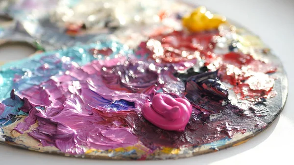 sanatçı bir fırça ile palette koyu rengi birbirine karıştırır..