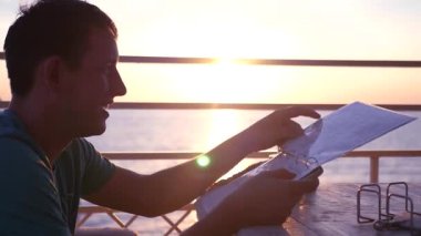 İyi bir ruh hali, genç bir adam bir gün batımı ile sahilde bir kafede oturup, Menide verilirse, bir seçim yapmak istiyor. HD, 1920 x 1080. ağır çekim