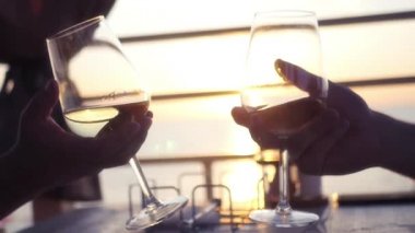 Gözlük şarap ile gün batımı ve deniz arka planı elinde tutan iki adam. HD, 1920 x 1080. ağır çekim