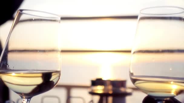 Two beautiful glass wine glasses with wine on a sunset background at sea. HD, 1920x1080. slow motion — Stock Video