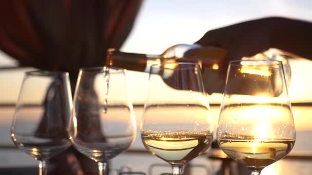 Verser le vin blanc savoureux dans des verres en verre avec un reflet du coucher de soleil et de la mer en eux. HD, 1920 x 1080. au ralenti — Video