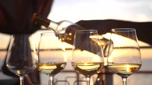 A party by the sea at sunset, pour wine into four glass glasses. HD, 1920x1080. slow motion — Stock Video