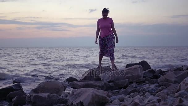 Una chica está caminando a lo largo de una playa cerca del mar. HD, 1920x1080. cámara lenta . — Vídeos de Stock
