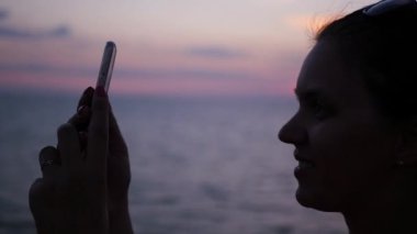 Güzel kız selfie deniz günbatımı bir arka plan üzerinde yapıyor. HD, 1920 x 1080. ağır çekim.