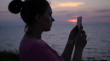 Bir kız güzel bir gün batımı bir fotoğraf denizin kenarında yapıyor. HD, 1920 x 1080. ağır çekim.