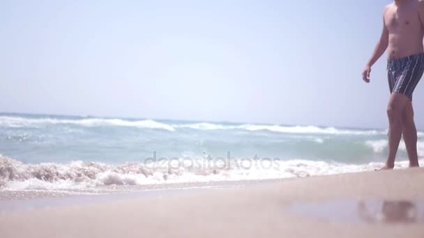 Мужчина убегает на песчаном пляже от волн. HD, 1920x1080. замедленное движение — стоковое видео