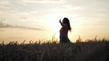 Kız bir buğday alanında ayakta ve güneşin ışınları geçen günde zevk. HD, 1920 x 1080. ağır çekim.