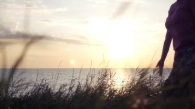 Denize sıfır plaj boyunca kız yürüyor, arka planı gökyüzü ve gün batımı Rüzgar etek geliştirir. HD, 1920 x 1080, ağır çekim.