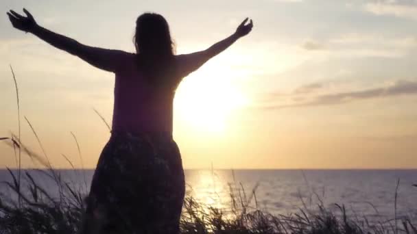 Flickan jublar över havet, solen och solnedgången, höjer händerna upp, virvlar. 4k, 3840 x 2160. HD — Stockvideo