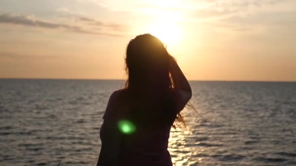 Une fille est debout sur la plage regardant au loin au coucher du soleil. 4k, 3840x2160. HD — Video