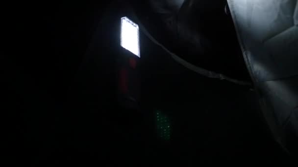 Eine hängende LED-Taschenlampe hängt in einem Touristenzelt, beleuchtet es innen. hd, 1920x1080. Zeitlupe. — Stockvideo