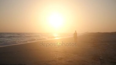 Deniz Sahil boyunca yürüyüş, bir lens etkisi ile günbatımı ışınları ile sular altında. HD, 1920 x 1080. ağır çekim.