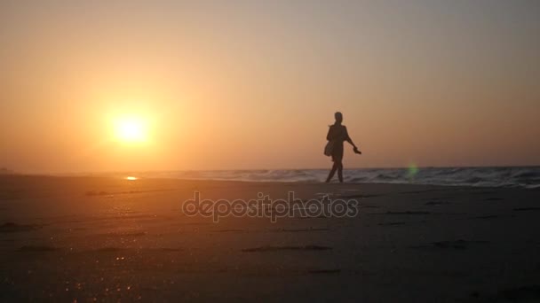 Wandelen alleen op een zandstrand aan de zee op een prachtige zonsondergang in de gouden stralen van de zon. HD, 1920 x 1080. Slow motion. — Stockvideo