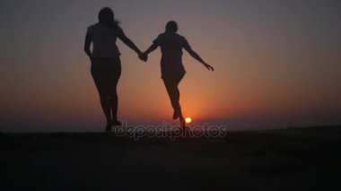 Sevinçle batımında sahilde elele atlama. HD, 1920 x 1080. ağır çekim.