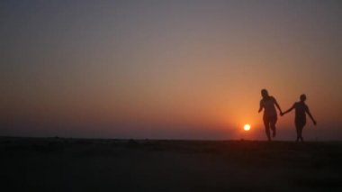 iki kız arkadaşım sevinçle batımında sahilde elele atlama. HD, 1920 x 1080. ağır çekim.