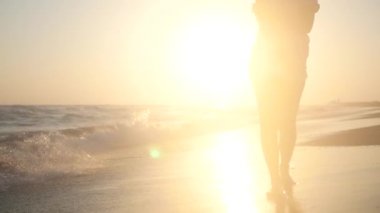 Kumlu bir plaj üzerinde günbatımında deniz kenarında walk Alone. HD, 1920 x 1080. ağır çekim.