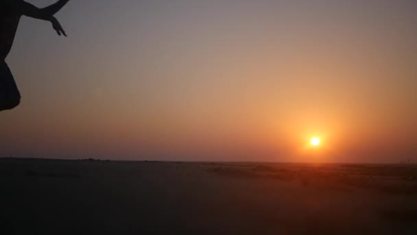 A man spoils and amuses himself running along the beach at sunset. HD, 1920x1080. slow motion. — Stock Video