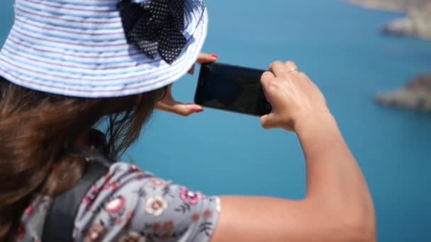 Dívka v fotografiruet modré moře krásný modrý klobouk z výše. HD, 1920 × 1080. Zpomalený pohyb. — Stock video