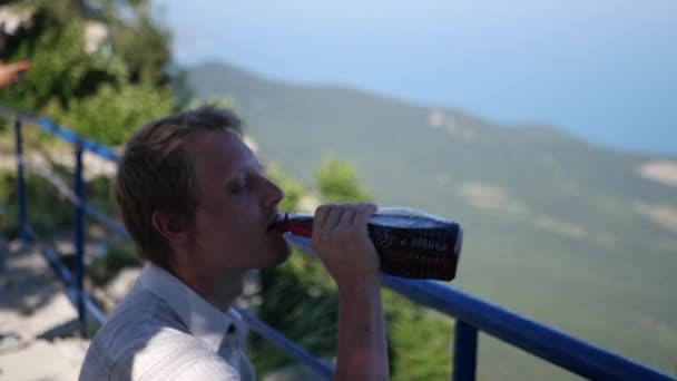 Un uomo che riposa all'altezza di una montagna bevendo vino da una bottiglia. HD, 1920x1080. rallentatore . — Video Stock