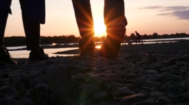 Gün batımında buzlu nehir kenarında yürüyüş. HD, 1920 x 1080. ağır çekim.