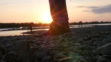 Spor ayakkabı içinde nehir kıyısında kayalık arazide yürüyüş. HD, 1920 x 1080. ağır çekim.