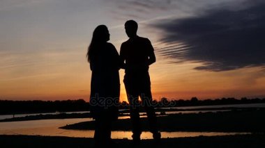 Gün batımı ile Nehri üzerinde romantik bir tarihte sarılma. HD, 1920 x 1080. ağır çekim.