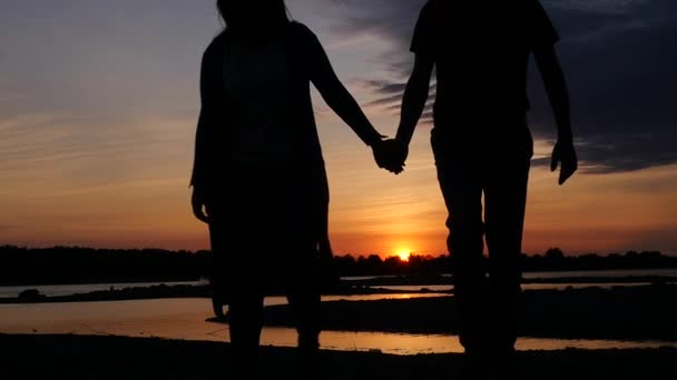 Una coppia amorevole che si tiene per mano camminando al tramonto lungo il fiume. HD, 1920x1080. rallentatore . — Video Stock