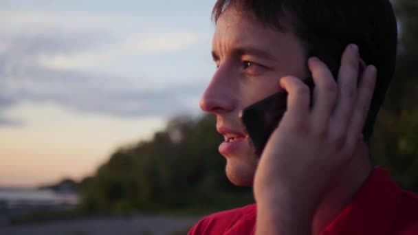 屋外の電話で話している若い男。クローズ アップ、スローモーション、1920 x 1080 の hd — ストック動画