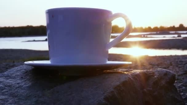 Sol al atardecer con rayos, escondido detrás de una taza de té caliente en una roca. Primer plano. cámara lenta, 1920x1080, hd — Vídeos de Stock