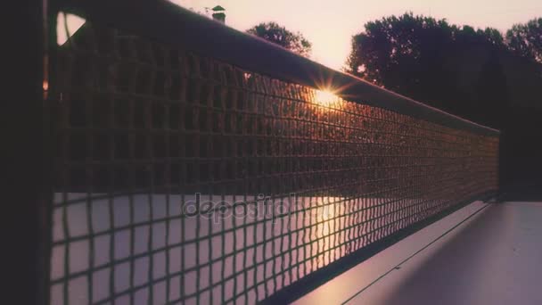 Promienie zachodzącego słońca slajdów na siatce tenis stołowy. szczelnie-do góry. slowmotion, 1920 x 1080, hd — Wideo stockowe