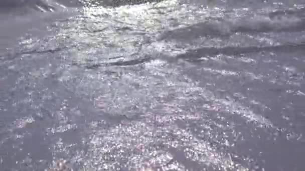 Záři slunce se odráží ve vodě, osamělá osoba stojí na kamenech nedaleko moře. 3840 x 2160, 4k — Stock video