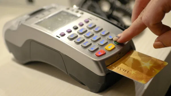 Bir kız kasiyer mağazada bir satış yapmak için bir banka terminali kullanır, cihaz üzerinden bir kart gerçekleştirir. Hd