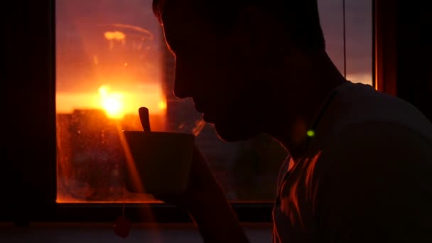 Πίνετε νόστιμα ζεστό τσάι στο ηλιοβασίλεμα από το παράθυρο με το εκτυφλωτικό φως του ήλιου. slowmotion, Hd, 1920 x 1080 — Αρχείο Βίντεο