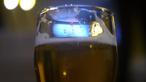 A glass of fresh beer close-up, with a blue and yellow blur. 3840x2160, 4K — Stock Video