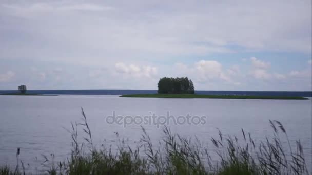 Krásná krajina u vody, s ostrůvkem a stromy a běžící oblaka. časová prodleva. 4k, 3840 x 2160. HD — Stock video