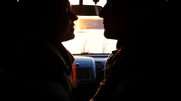 Hombre y mujer están sentados en el coche al atardecer, besándose y sonriendo. cámara lenta, 1920x1080, full hd — Vídeos de Stock