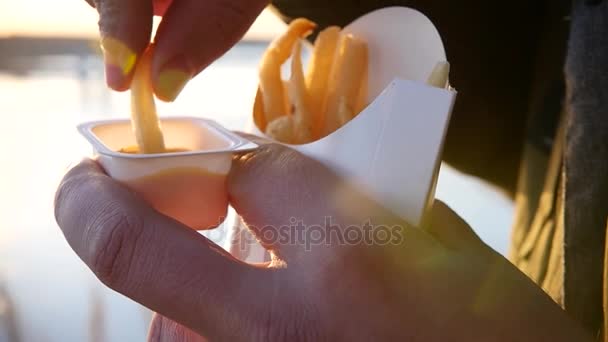 Окунитесь в соус вкусной, жирной картошки фри на улице против заката. slow motion, 1920x1080, полный привод — стоковое видео
