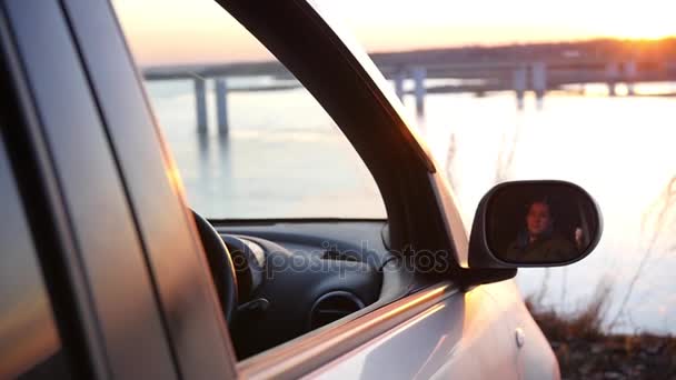 Un hombre está sentado en el coche en el estacionamiento y admirando la hermosa vista y puesta de sol en la ventana abierta del coche. slow motion, Gran Pito, 1920x1080 — Vídeos de Stock