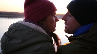Erkek ve kadın gün batımında nehir kenarında öpüşme şapka. Slowmotion, Hd, 1920 x 1080