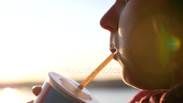 A fat girl chews and drinks soda through a tube at sunset with a lens effect. slowmotion, HD, 1920x1080 — Stock Video