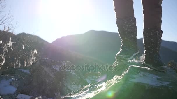 Agitar la nieve de las botas, de pie sobre una roca cubierta de nieve resbaladiza en los rayos del sol. cámara lenta, 1920x1080, full hd — Vídeos de Stock