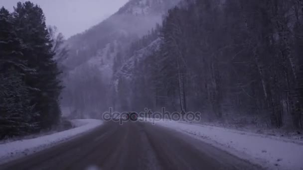 Draußen im Auto auf einer schneebedeckten schlechten Straße, durch Wald und Berge. 3840x2160, 4k — Stockvideo