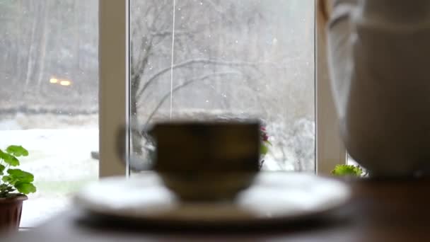 Fuera de la ventana en el bosque nieva, el foco se mueve a una taza de té caliente en un café. cámara lenta, 1920x1080, full hd — Vídeo de stock