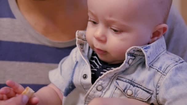 The kid sits in the arms of his father and he eats a piece of apple.. slow motion, 1920x1080, full hd — Stock Video